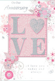 This softly glowing anniversary card echoes the quiet romance of an evening stroll past the houses around Blackheath, where warm lamplight spills out onto tree-lined streets. Dominating the centre of the design, the word LOVE stands proudly in raised letters that feel smooth and slightly ridged beneath the fingertips. Each letter is filled with a soft, pearlescent white and outlined in a fine rim of silver glitter, giving a gentle sparkle that never feels overpowering. Beneath and behind the lettering lies a calm blush-pink background, even in tone and reminiscent of the inside of a pale rose petal. Around this central element, a delicate spray of illustrated flowers and swaying foliage spreads across the card. The blossoms are small and stylised, with rounded petals shaded in blush pink, mauve, and creamy ivory, their outlines drawn with a careful, almost calligraphic hand. Touches of silver foil highlight select petals and leaves, catching the light like dew glinting on the grass at the edge of Blackheath on an early morning. Slender stems and curling tendrils weave among the blooms, giving a sense of gentle motion and the organic looseness of a hand-tied bouquet. The floral motifs frame the word LOVE without enclosing it, leaving breathing space that lets the design feel calm and uncluttered. Across the composition, in elegant script lettering, are written heartfelt anniversary messages-phrases that speak of lasting affection, gratitude, and shared years together. The script is refined and flowing, pairing beautifully with the soft colours and subtle shimmer. This card looks and feels like a carefully composed floral tribute in paper form, ideal for expressing enduring love on an anniversary celebrated in Blackheath or sent to someone special further afield.